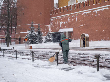 Moscow. Russia. February 12, 2021. Utility workers remove snow with a snow blower and shovels during...
