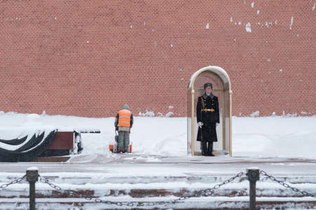 Moscow. Russia. February 12, 2021. A utility worker cleans snow with a snowplow at the grave of the Unknown Soldier in the Kremlin during a snowfall. A guard of honor is on duty at the eternal flame.のeditorial素材