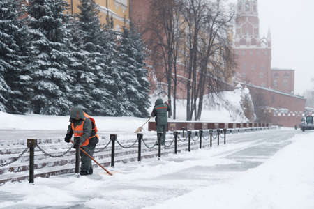 Moscow. Russia. February 12, 2021. Utility workers remove snow with shovels during a snowfall near the Kremlin wall at the grave of the Unknown Soldier on a winter day.のeditorial素材