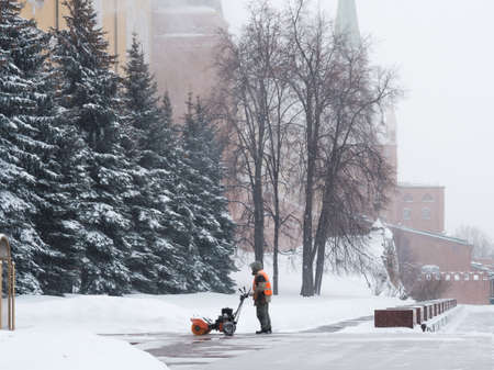 Moscow. Russia. February 12, 2021. A utility worker uses a snowplow to remove snow from the walls of the Kremlin during a heavy snowfall on a winter day. Snowflakes are flying in the air.のeditorial素材