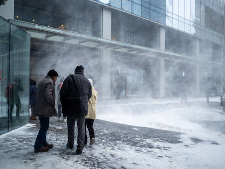 Moscow. Russia. February 12, 2021. Natural disasters. People walk along the building through a blizzard with heavy snowfall. A snow cyclone covered the city.のeditorial素材