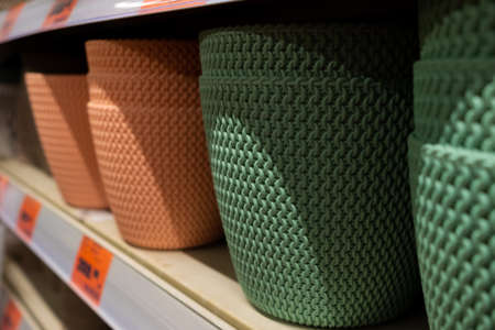 Selective focus on flower pots on a garden store shelf. Lightweight, beautiful plastic pots in...