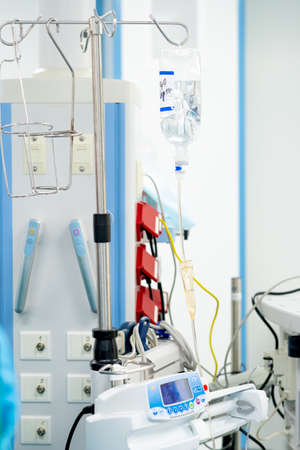 Infusion dropper on a medical stand in a surgical operating room. Transparent plastic bottle with...