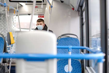Moscow. Russia. March 26, 2021. A young man in a city bus wearing a protective mask. Prevention and protection against viral infections.のeditorial素材