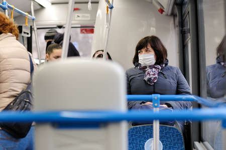 Moscow. Russia. March 26, 2021. An adult woman in a medical protective mask sits on a seat in a bus....