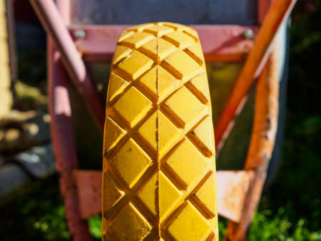 Selective focus on the tread of the yellow wheel of the garden cart. Blurred background. Summer sunny day.の写真素材
