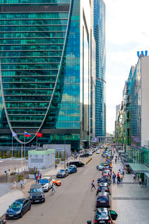 Moscow. Russia. May 26, 2021. View of the city street with skyscrapers of the Moscow-City business center on a sunny day. Many cars and motorcycles are parked along the road, people are walkingのeditorial素材