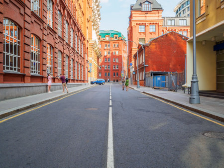 Moscow. Russia. June 26, 2021. A wide-angle view of a side street in the center of Moscow on a sunny summer day with few people. Old red brick buildings of the former Red October confectionery factoryのeditorial素材