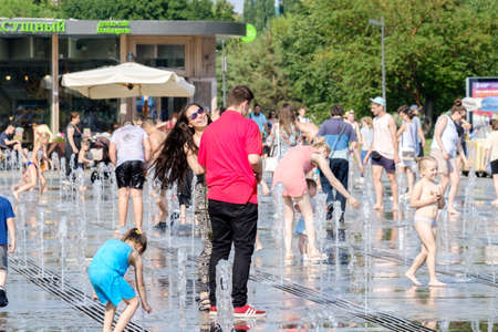 Moscow. Russia. June 26, 2021. A couple in love, a girl and a guy hug and laugh between splashing water in a fountain. Hot summer day in the city.のeditorial素材