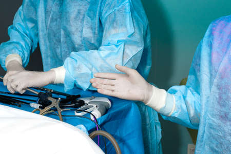 Hands of surgeons in sterile gloves and surgical instruments. Laparoscopic manipulators in the hands of a surgeon. Selective focus. Minimally invasive laparoscopic proctological surgery.の写真素材