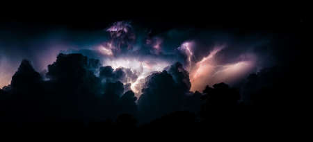 Flashes of lightning and clouds during thunderstorms at night. Panoramic photo.の写真素材