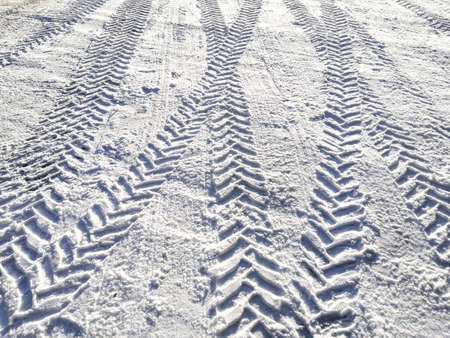 Traces of car tires in the snow in the light of the bright sun