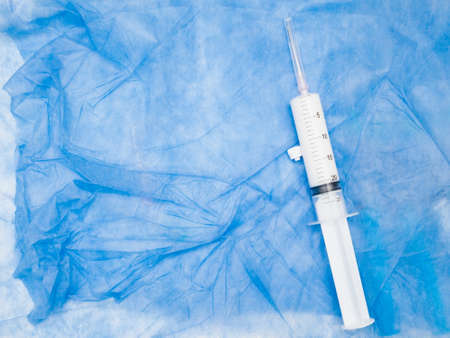 A large white syringe with an anesthetic medicine on a crumpled blue medical diaper. Top view. Flat layout. Copy space.の写真素材