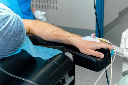 Anesthesia catheter in human hand during surgery. Selective focus. Intravenous drip catheter in the patients hand on the operating table. General anesthesia during surgery.の写真素材
