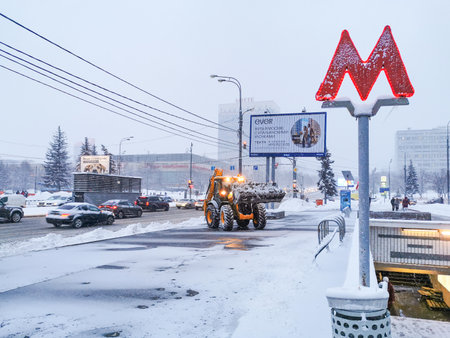 Moscow. Russia. January 18, 2022. A tractor cleans snow near the exit of a Moscow metro station during heavy snowfall.のeditorial素材