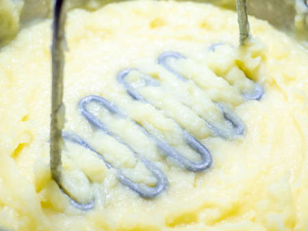 Metal potato masher in freshly made mashed potatoes. Selective focus. Pestle for making mashed potatoes close-up.の写真素材