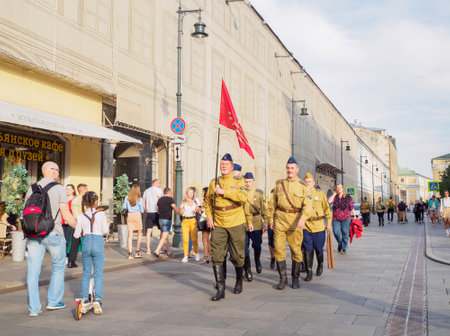 Moscow. Russia. May 9, 2021. A group of men in the form of Soviet soldiers with a red banner is marching down the city street. Procession in honor of the Victory Day in the Great Patriotic War.のeditorial素材