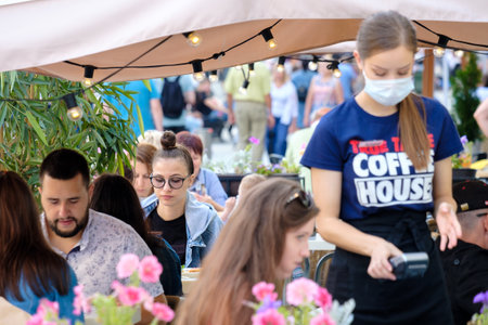 Moscow. Russia. August 1, 2021. A young girl with glasses sits at a table in an outdoor cafe in the city. Selective focus. Crowded street cafe.のeditorial素材