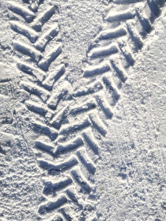 Traces of car tires in the snow in the light of the bright sunの写真素材