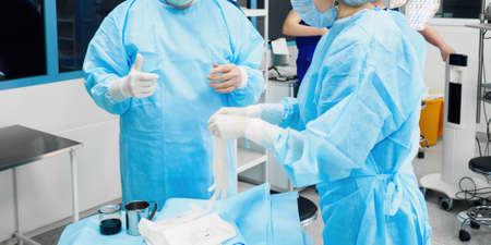 Surgeons help each other put on sterile surgical gloves. Selective focus.の写真素材