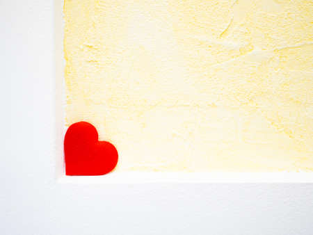 Red heart on a yellow wall. Red heart as a symbol of love and compassion. Valentines Day. Copy space for your text.の写真素材