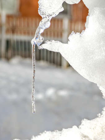 Clear icicle on a sunny day in the spring. Frozen water shines in the sunlight. Blurry background. Selective focus.の写真素材