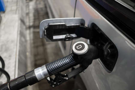 A pistol with diesel fuel in the mouth of a gas tank at a gas station. Selective focus. The concept of the global fuel crisis and rising energy prices.の写真素材