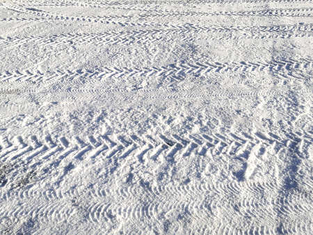 Traces of car tires in the snow in the light of the bright sunの写真素材