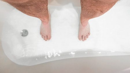Selective focus on hairy male legs in a bath of water. View from above.の写真素材