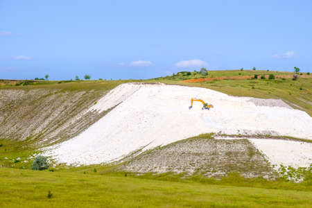 A yellow excavator works in a chalk quarry.の写真素材