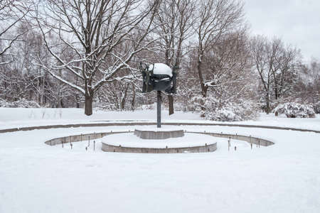 Moscow. Russia. April 3, 2022. Snow-covered frozen fountain in the city park. Fountain with a sculptural composition in the snow.のeditorial素材