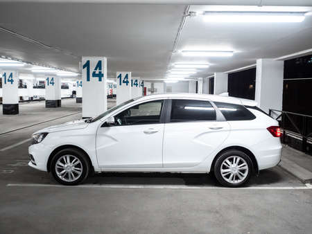 Moscow. Russia. September 15, 2021. Side view of a white car Lada Vesta SW, made in the station wagon body. Modern Russian car Lada Vesta SW on an empty parking lot at night.のeditorial素材