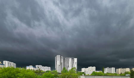 Dark storm clouds shroud the sky over city blocks. Stormy weather in the city.の写真素材