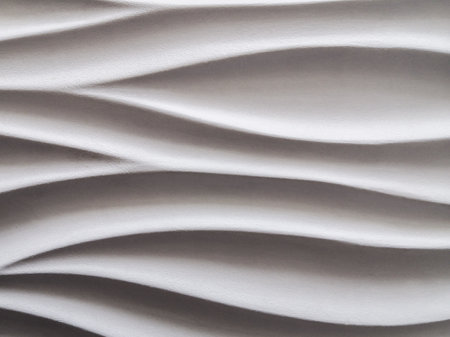 Abstract background formed by smooth wavy lines of gypsum on the wall. The difference of lights and shadows on a relief surface.の写真素材
