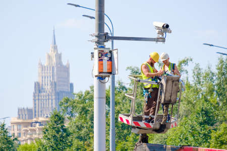 Moscow. Russia. June 9, 2022. Engineers on a tower crane repair a CCTV camera on a pole in the city. Selective focus.のeditorial素材