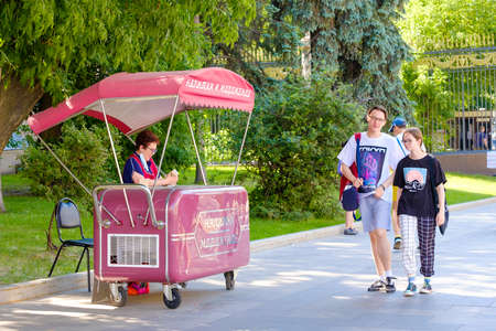 Moscow. Russia. June 9, 2022. Mobile ice cream kiosk on the street in Moscow. Selective focus. A woman seller sells ice cream from a refrigerator on a city street on a sunny summer day.のeditorial素材