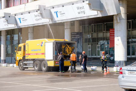 Moscow. Russia. June 9, 2022. A public utility worker washes the facade of a building with a water jet from a hose on a sunny summer day. Public service work in Moscow.のeditorial素材
