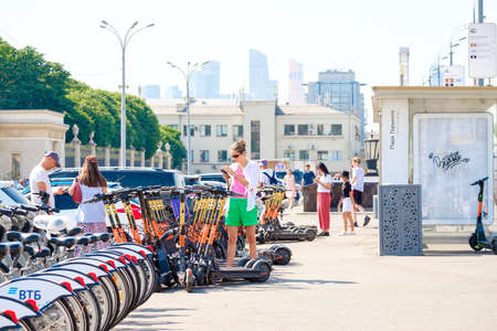 Moscow. Russia. June 9, 2022. People rent electric scooters and bikes using smartphone apps. Selective focus. The concept of using zero-emission transport in the city.のeditorial素材