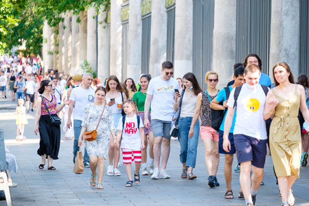 Moscow. Russia. June 9, 2022. Selective focus on a happy couple in a crowd of people walking along the sidewalk in the city on a summer day.のeditorial素材
