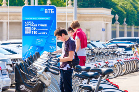 Moscow. Russia. June 9, 2022. A young man chooses a bicycle to rent on a sunny summer day on a street in Moscow. Selective focus. Public environmentally friendly transport in the city.のeditorial素材
