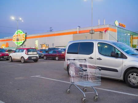 Moscow. Russia. June 7, 2022 Shopping trolley and cars in the parking lot of the Globus hypermarket on a summer evening.のeditorial素材