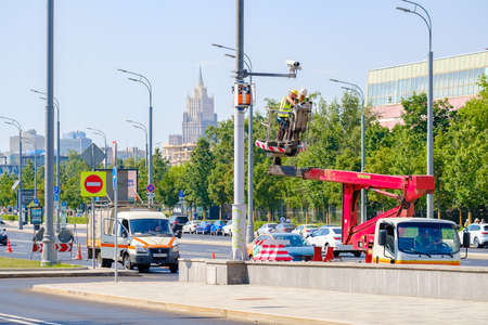 Moscow. Russia. June 9, 2022. Electronic engineers in a cart of a mobile tower repair a security camera on a pole on a street in Moscow. Selective focus.のeditorial素材