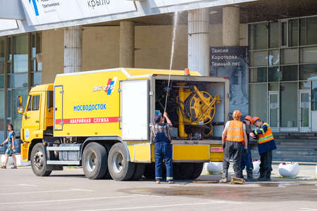 Moscow. Russia. June 9, 2022. City utility service washes the facade of the building. A worker sprays a jet of water from a hose on a sunny summer day. Public service work in Moscow.のeditorial素材