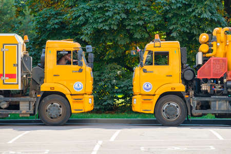 Moscow. Russia. June 9, 2022. Two yellow trucks of the Mosvodostok city service against the background of green foliage of trees. Machines for drainage of roads and sewers.のeditorial素材