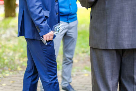 Empty glass champagne flute in male hand. Selective focus. A man in a blue suit holds an empty wine glass.の写真素材