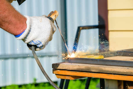 Electric arc welding electrode in the welders hand. Selective focus. Sparks and flashes during...