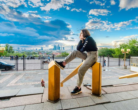 Moscow. Russia. July 1, 2021. A pretty young girl poses while sitting against the backdrop of the...