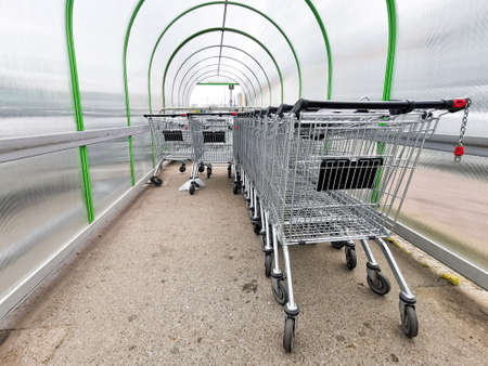 Many shopping trolleys under a semi-circular polycarbonate canopy. Shopping carts are parked near the hypermarket under a canopy.の写真素材