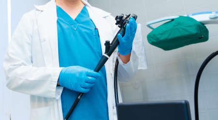 Selective focus on doctors hands holding an endoscope. Doctors hands in sterile gloves hold an endoscope for colonoscopy and early detection of cancerous tumors in the intestine.の写真素材