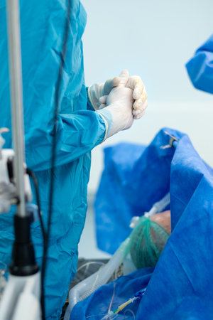 Crossed fingers of a surgeon in sterile gloves. Selective focus. The surgeon stands over the patient lying on the operating table.の写真素材